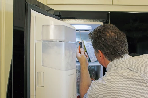 Appliance repair tech servicing a refrigerator