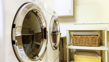 Washer and dryer in a utility room, next to a shelf holding two large wicker baskets.