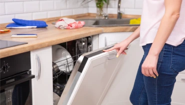 Individual turning an open dishwasher on.