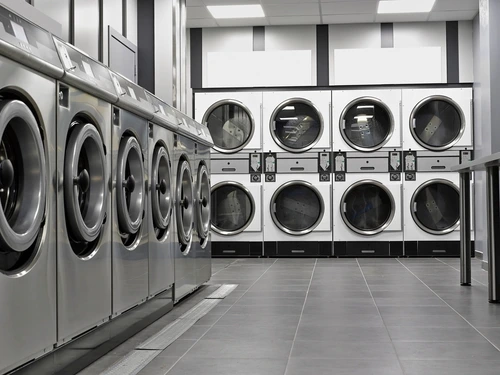  Row of industrial washing machines and dryers in a public laundromat