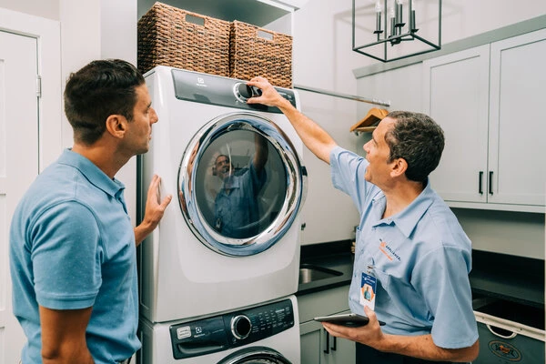 Issaquah homeowner and Mr. Appliance washer repairman in laundry room inspecting stackable washer and dryer