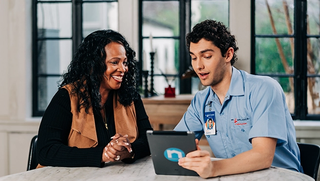 A Mr. Appliance technician speaks with a customer while sitting at a table.
