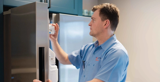 A Mr. Appliance technician looks inside of a client?s freezer.