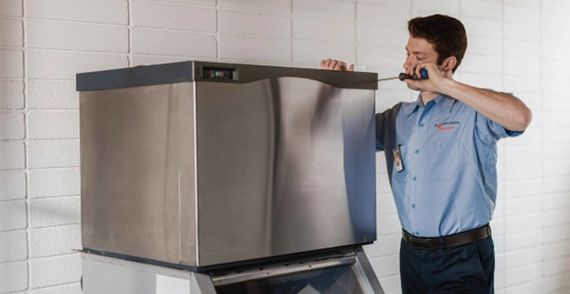 A Mr. Appliance technician inspects an ice machine.