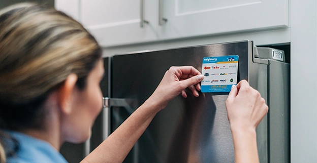 A Mr. Appliance technician places a fridge magnet on a refrigerator.