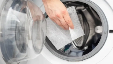 Someone adding a dryer sheet to their dryer.