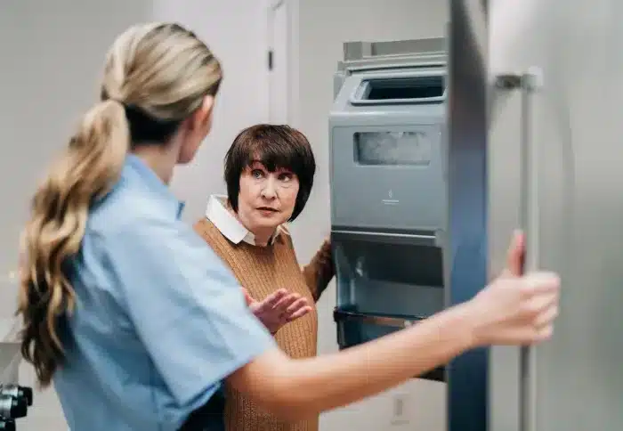 Mr. Appliance service professional inspecting a stainless steel refrigerator in a kitchen.