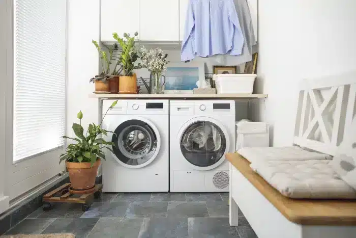 Modern white front-load washing machine and dryer side by side in a clean home laundry room.