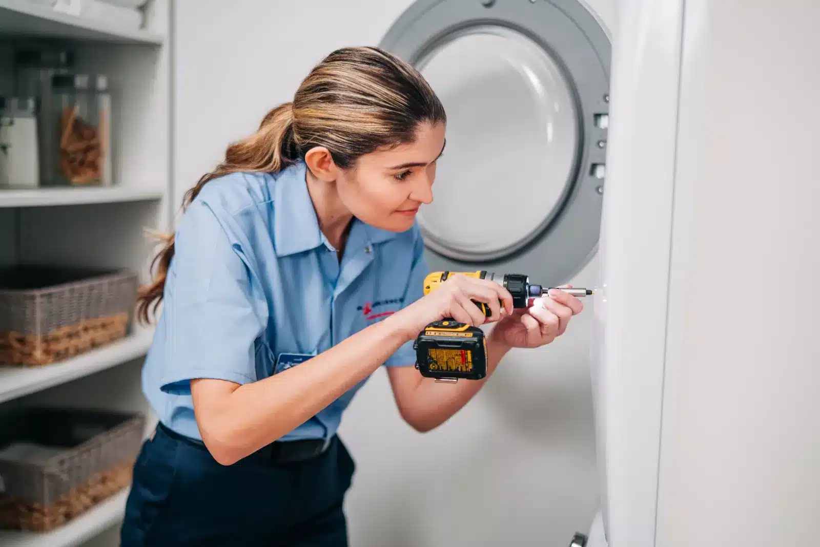 Uniformed Mr. Appliance service professional performing maintenance on a laundry appliance.