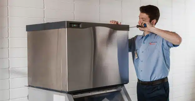 Mr. Appliance service professional working on top of ice machine.