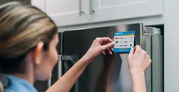 Mr. Appliance service professional applying brand sticker on front of refrigerator.
