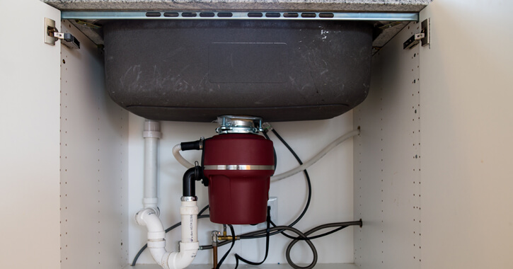 A garburator, or garbage disposal, installed underneath a sink.