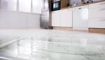 Standing water covering a white kitchen floor.