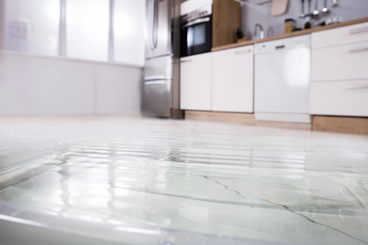 Standing water covering a white kitchen floor.