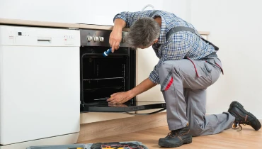 Appliance repair tech servicing an oven