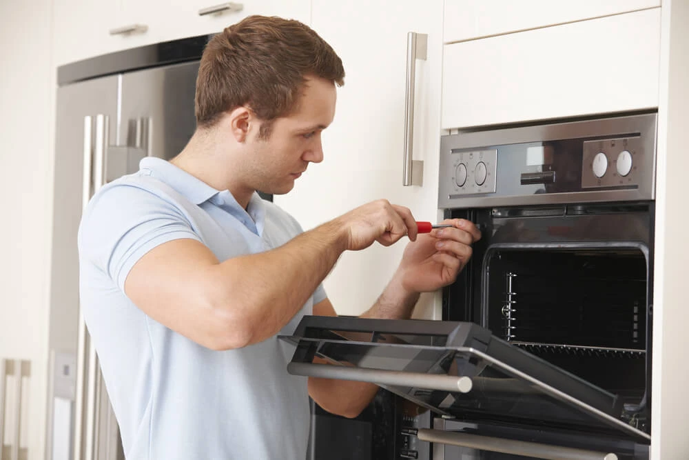 Appliance repair tech servicing an oven