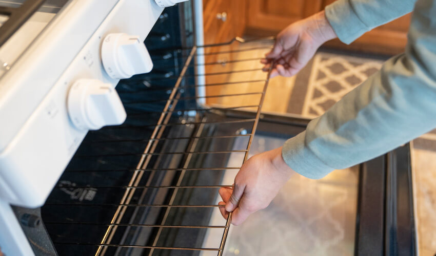 Person pulling metal grate out of an oven