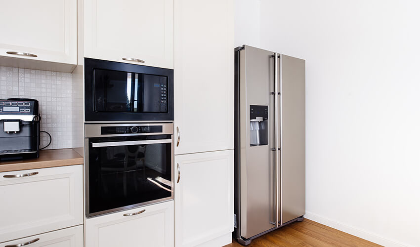 Bright kitchen with refrigerator, oven and microwave