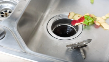 Discarded food in a stainless steel sink that’s been extracted from a garbage disposal that’s not working.