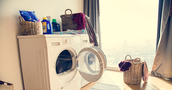 Open washing machine in front of a window showing a bright city
