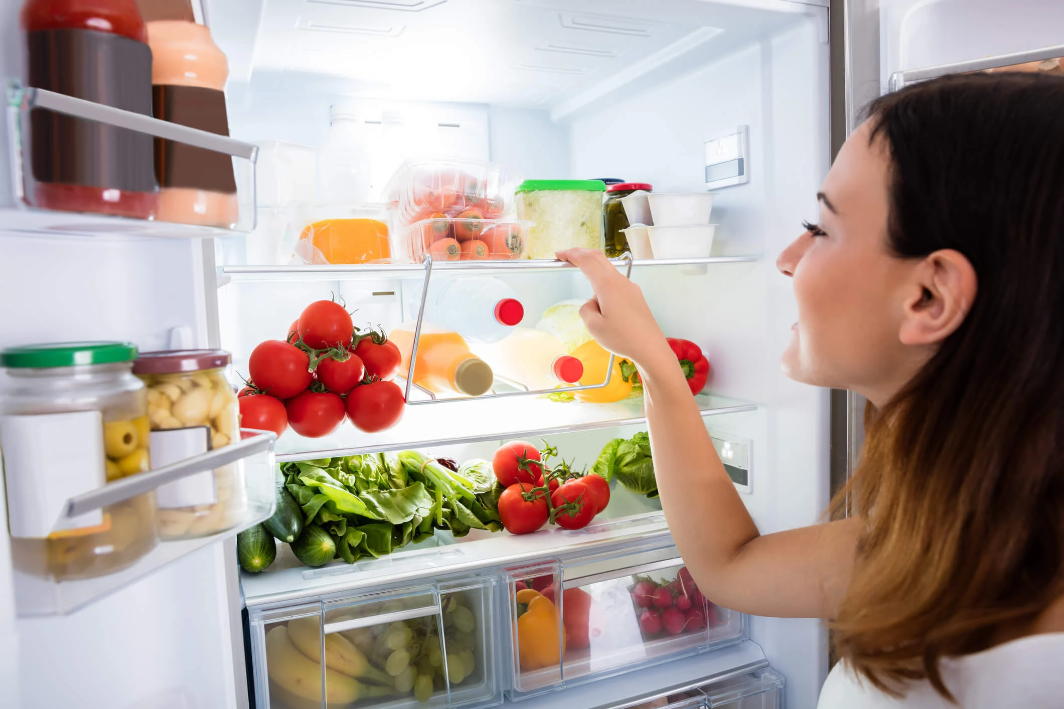Woman getting food out of refrigerator