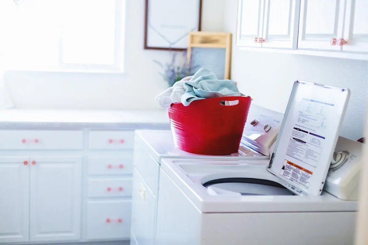 Open top-loader washing machine in an all-white laundry room | top-load-washer