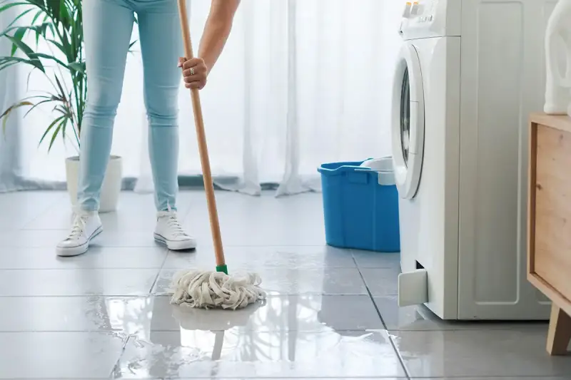 Person mopping up water because a washing machine is leaking | washing-machine-leaking-hero