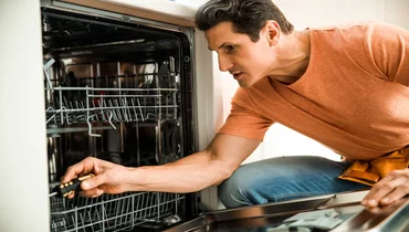 Technician checking the inside of a dishwasher.