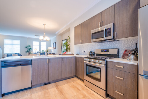 A modern, bright kitchen with driftwood-brown-colored cabinets and stainless-steel appliances.