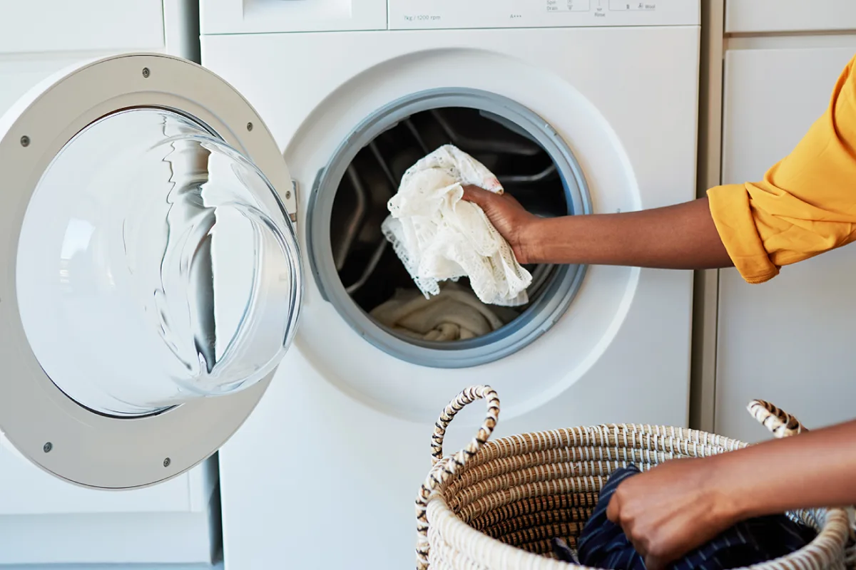 A person uses their washing machine after getting rid of washing machine smells.