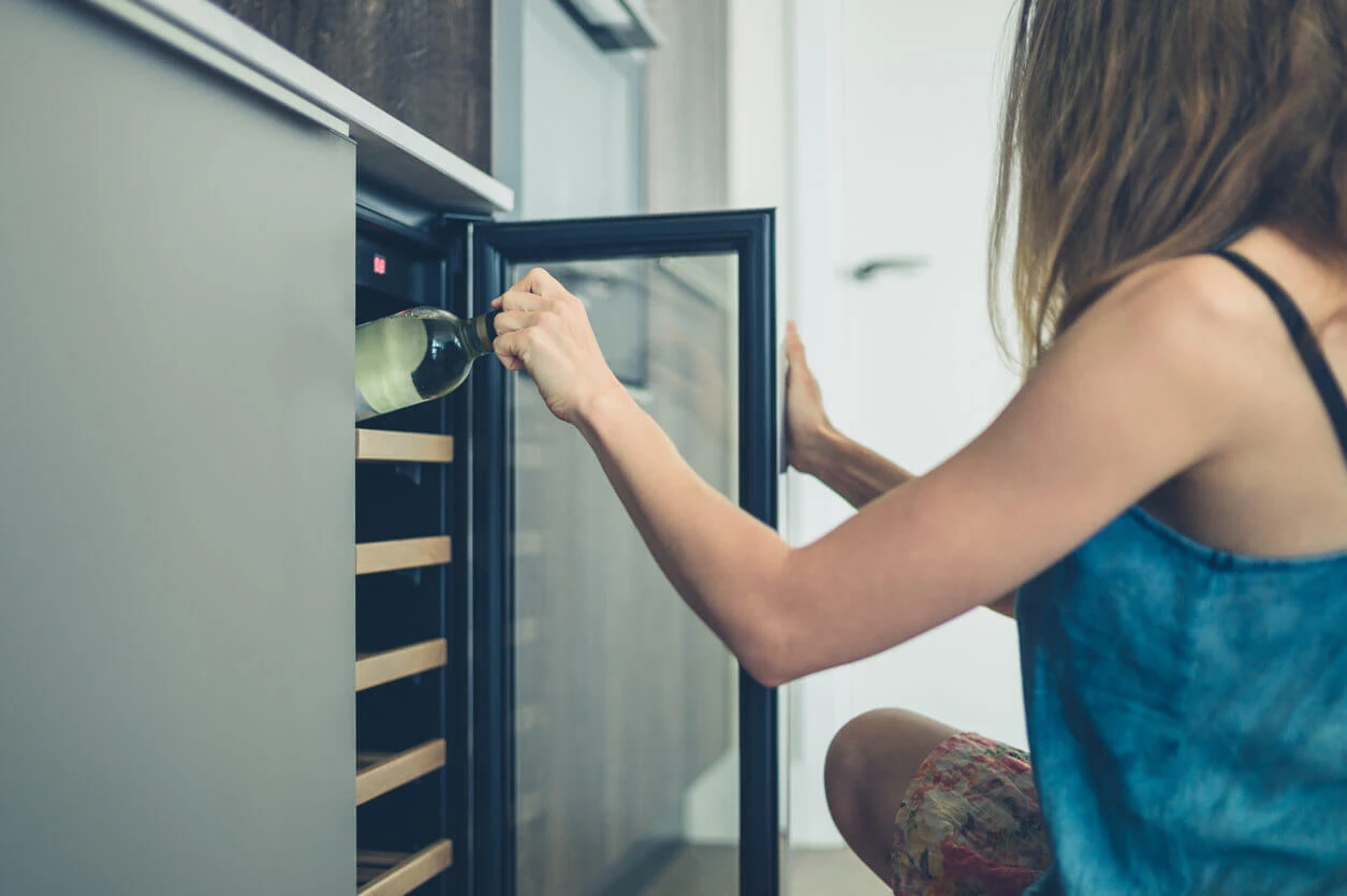 Woman opening wine refrigerator