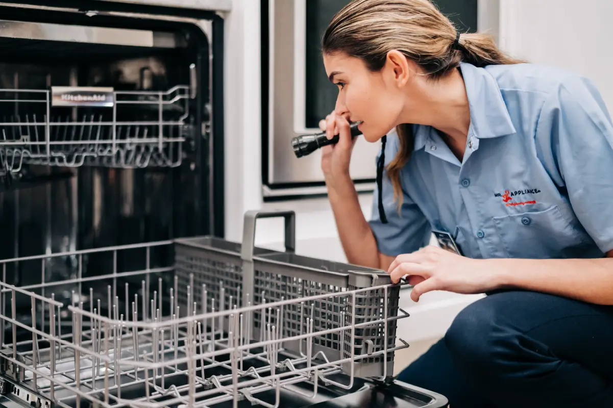 Mr. Appliance service specialist inspecting a dishwasher.