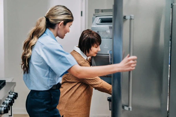 Service Professional helping a homeowner fix a refrigerator not cooling