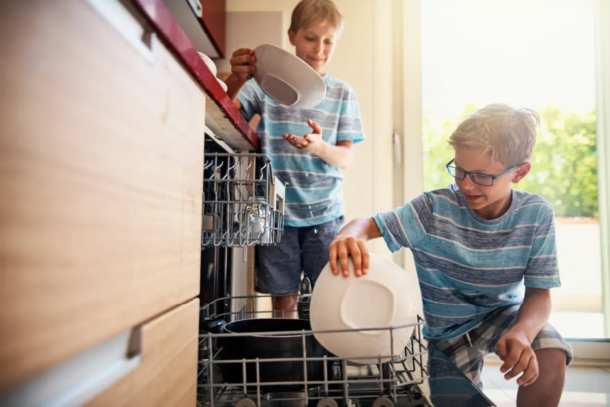Two kids loading dishes into a dishwasher properly.