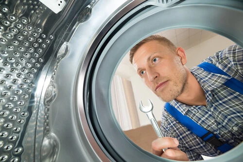 Appliance repair tech servicing a washer