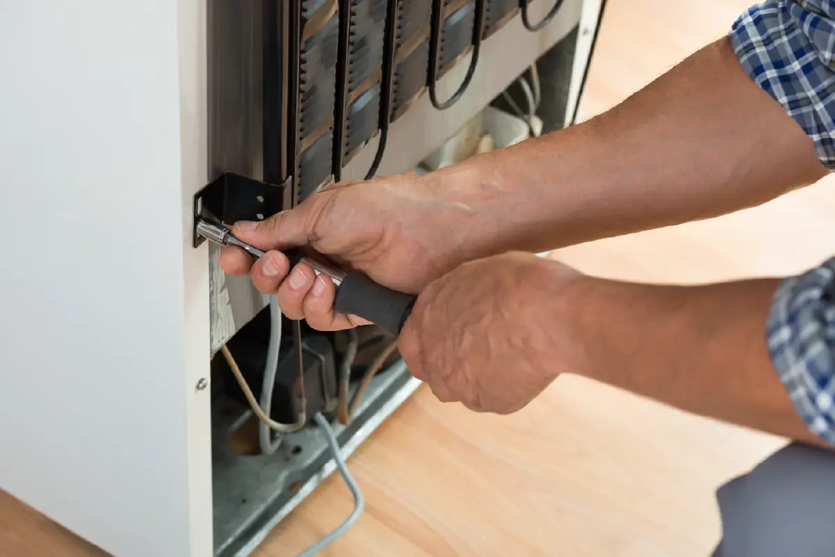 Person fixing a refrigerator leaking water.