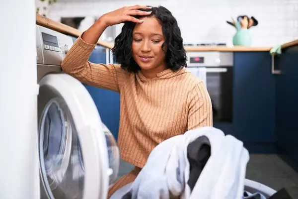 Woman looking frustrated at clothes out of the dryer.
