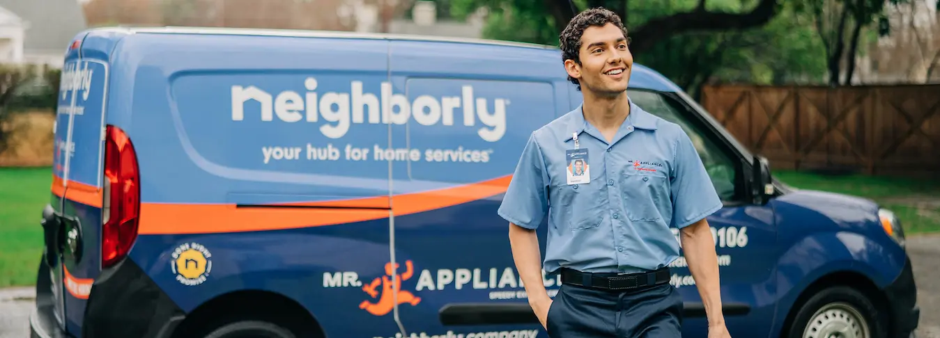 Mr. Appliance technician smiling in front of branded van.  