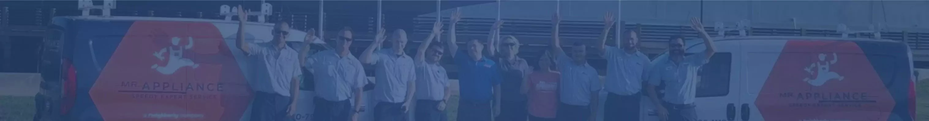 Row of Mr. Appliance technicians waving between pair of branded vans. 