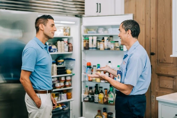 A Mr. Appliance repairman talking to a customer about their refrigerator