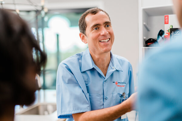 Mr. Appliance technician in booties unpacking tool bag in residential kitchen.