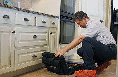 Mr. Appliance technician repairing appliance.