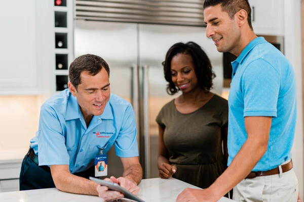 Mr. Appliance tech reviewing appliance repair service info with two homeowners