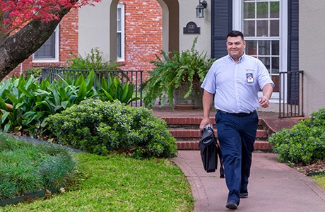 A Mr. Appliance technician walking outside a residential home.