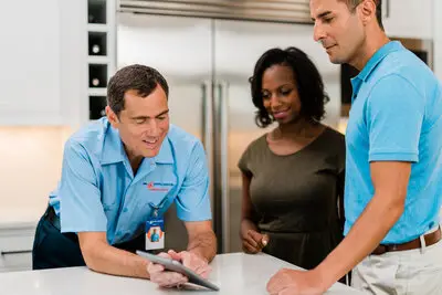 A professional Mr. Appliance dishwasher repairman reviewing estimate with two happy customers
