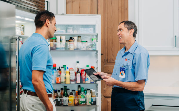A customer and Mr. Appliance tech discussing refrigerator repairs in a kitchen