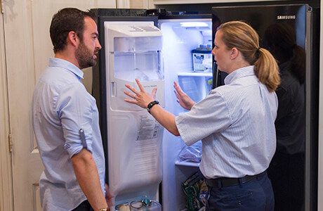 Mr. Appliance tech assessing refrigerator with homeowner