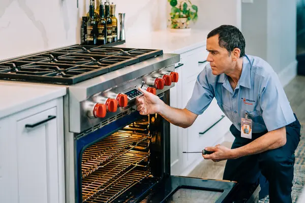 Mr. Appliance tech repairing a range in kitchen