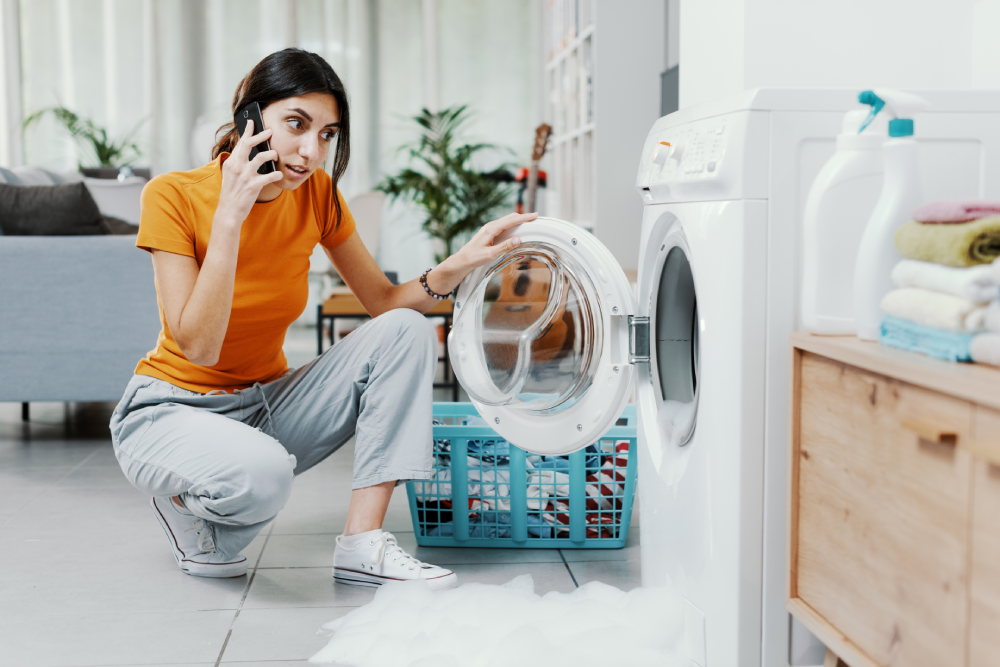 Concerned woman sitting in fornt of washing machine using her cell phone to call Mr. Appliance.