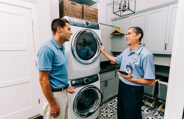 Olympia homeowner and Mr. Appliance technician in laundry room discussing washer and dryer repairs.